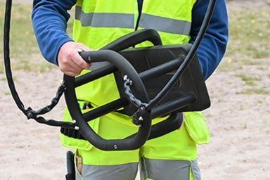 Besiktningsman i varselväst bär lekplatsutrustning